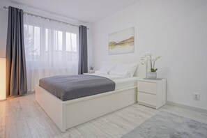 Bedroom with queen size bed, clothing storage, cotton linens and black out curtains.