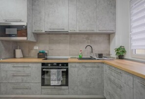 Fully equipped kitchen with fridge, freezer, oven, stove, coffee espresso machine, toaster, water kettle, microwave, cooking utensils, cooking basics and dining table.