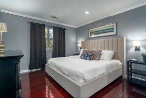 Master bedroom with king bed and flat-screen TV, featuring an ensuite master bathroom.