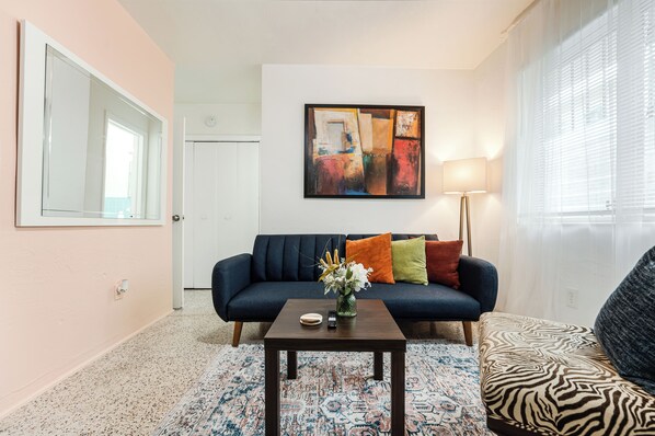 Spacious living room with futon, a flat-screen TV, and a large window that let in plenty of natural light. 