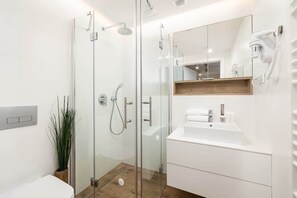 The bathroom's contemporary design includes fresh towels and a hairdryer. 
