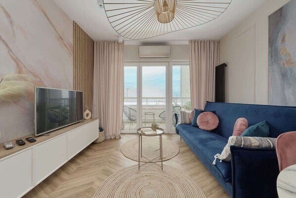 A stylish living area with a modern TV unit, a large window with curtains, and a cozy sofa.