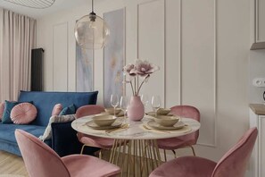 A bright, open-concept living space with a pink and gold-themed dining area and modern furniture.