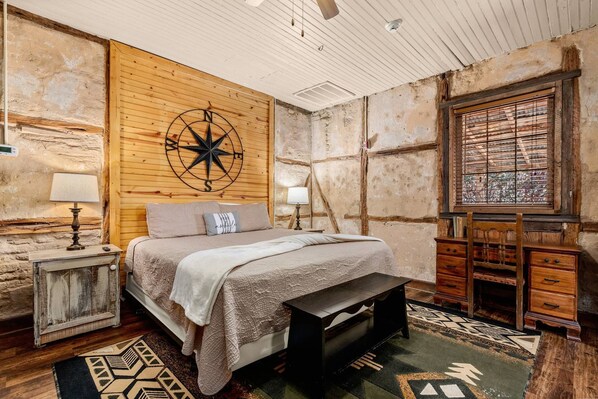 The primary room boasts a regal king-size bed, nightstands and matching reading lamps, and a desk.