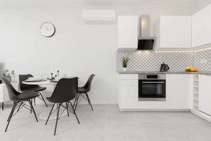 A modern open-concept kitchen with a black dining table and chairs.