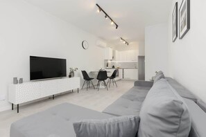 A spacious living room with a large gray sofa, a TV, and a black-and-white interior design.