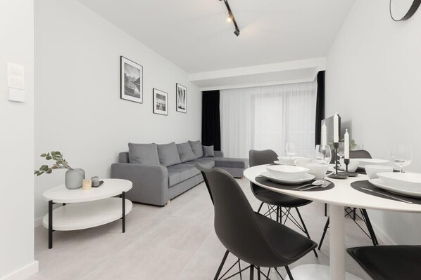 A modern living room with a gray sofa, black dining chairs, and elegant black-and-white decor.