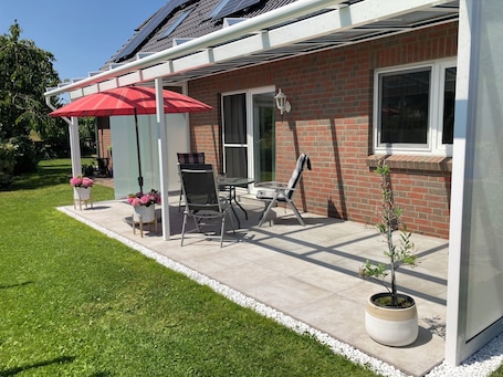 große überdachte Terrasse mit Tisch, 4 Stühlen, Beistelltischen und Sonnenschirm