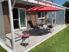 große überdachte Terrasse mit Tisch, 4 Stühlen, Beistelltischen und Sonnenschirm