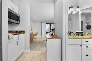 A hallway leading to a bathroom and a compact kitchen equipped with a microwave.A hallway leading to a bathroom and a compact kitchen equipped with a microwave.