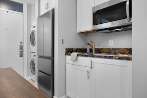 A compact kitchen equipped with a refrigerator and an integrated washer and dryer.