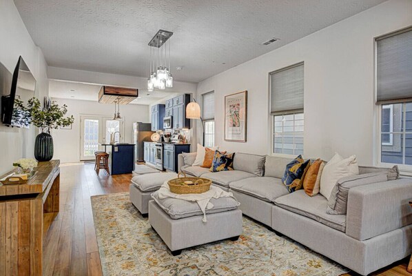 Welcome to a bright, open-plan living room with seamless flow into the dining and kitchen areas. Enjoy a large Smart TV and relax on a comfortable modular couch—perfect for unwinding after a day of exploring.