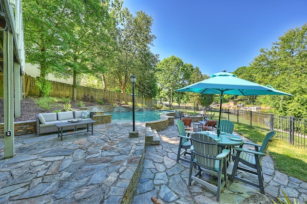 Bar top table with shade, pool loungers and Adirondack seating on the pool deck.