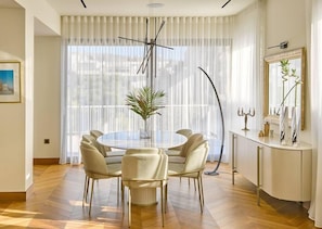 Experience refined dining in our Athens Penthouse showcased in this image—a luminous and beautifully appointed dining area. The oval table adds an elegant touch, creating a space where every meal becomes a delightful occasion in the heart of luxury