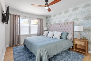 The master bedroom boasts sumptuous linens, blackout shades for uninterrupted rest, a whisper-quiet ceiling fan, and a smart TV, offering a sanctuary of comfort and relaxation.