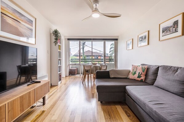 The open-plan living space is complete with a comfy sofa and TV, while glass doors open out to a private balcony.  
