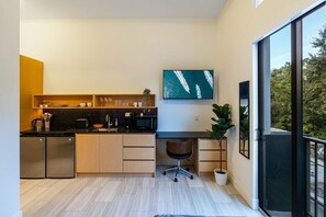 Fully equipped kitchen with workstation, office chair, 55" smart TV, and small balcony