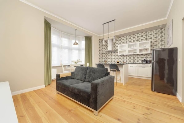 A stylish living area with a modern sofa, a TV stand, and a kitchenette with open shelving.