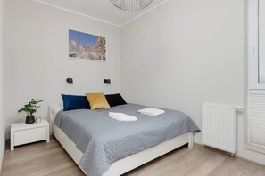 A comfortable bedroom with a double bed, grey bedding, and minimalist decor.