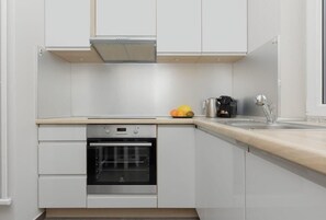 A bright and modern kitchen with white cabinets, a built-in oven, and a minimalist design. The kitchen looks clean and functional.