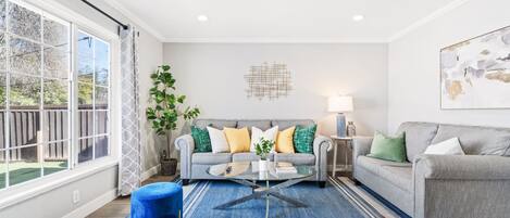 Chic living area with vibrant accents, plush sofas, and ample light. 