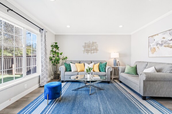 Chic living area with vibrant accents, plush sofas, and ample light. 