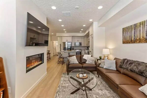 Cozy living room with fireplace, open to the kitchen.