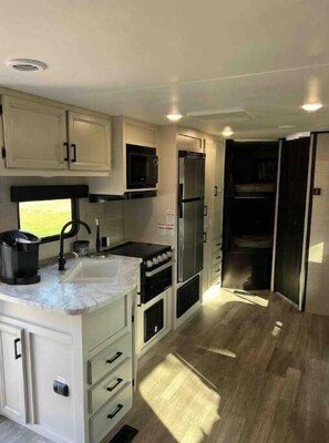 Kitchen with sink, microwave, range, refrigerator/freezer, and lots of storage. 