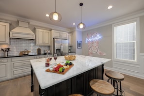 2nd Floor: Fully-equipped kitchen with stainless steel appliances, basic cooking essentials, a large island with bar seating, and wet bar.
