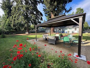 Large private backyard with outdoor seating, a fire table and lighted gazebo. 