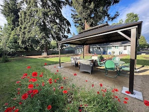 Large private backyard with outdoor seating, a fire table and lighted gazebo.