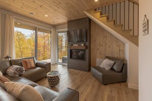 Living room with fireplace, armchair, and wood-paneled ceiling