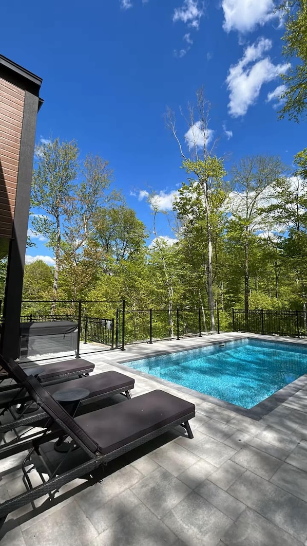 Poolside loungers under bright blue sky and lush trees