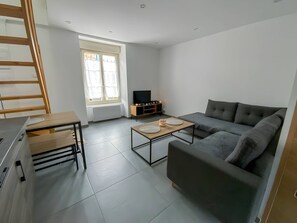 "Modern Living Room: Corner Sofa, TV, Window, Gray Tiles"