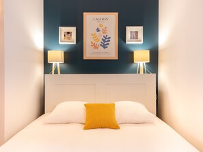 "Zona de dormitorio con cama doble grande y pared azul pato".