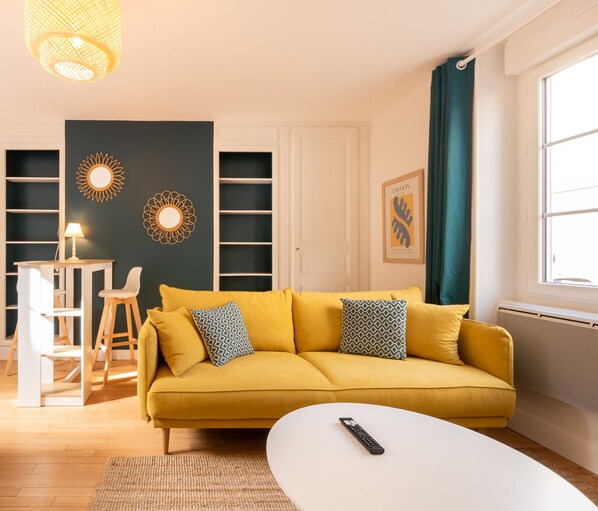 "Lounge area with yellow sofa, duck blue wall and white shelves"