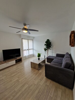 "Lounge area with coffee table, sofa, French window, TV unit and ceiling fan".