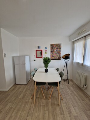 "Dining area with table, fridge and wall decoration".