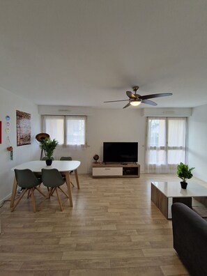 "Lounge area with coffee table, sofa, dining table, windows, TV cabinet and ceiling fan"