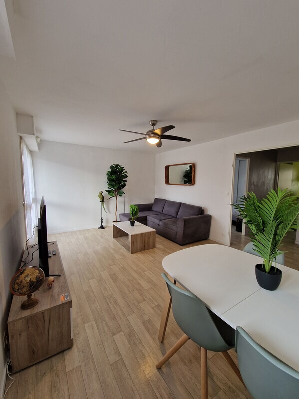 "Living room with dining table, TV stand, sofa and green plants".