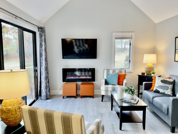 Living room features a vaulted ceiling and sliders leading out to the deck. 