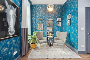 Compact room, blue accent wall, framed artwork, with two chairs.