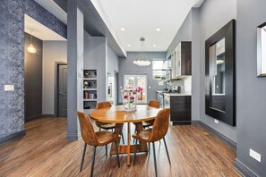 Wide view of the kitchen with chairs on warm hardwood floors.