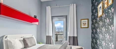 A close view of the bedroom with comfortable queen size bed, balcony door, curtains, and stylish wall decor.