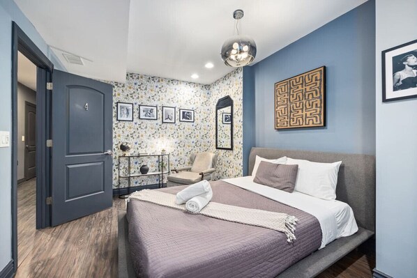 A cozy and stylish bedroom with a comfortable bed, a patterned armchair, and a unique wall decoration.