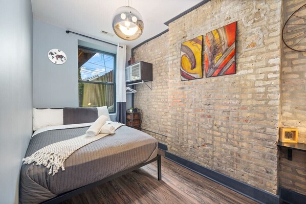 A  cozy and modern bedroom with brownish paper wall, a comfortable queen size bed, a large window with natural light, and stylish artwork.