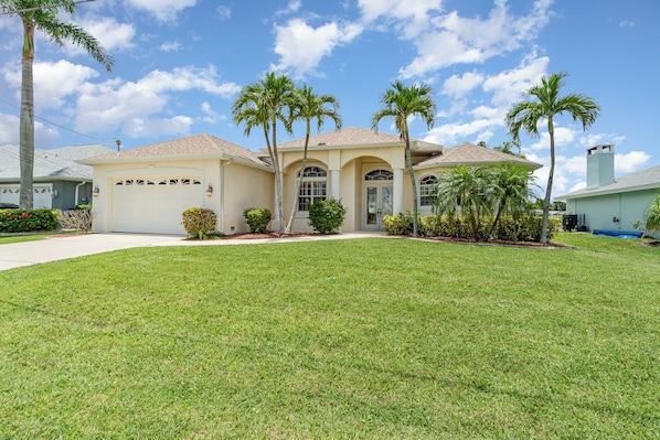 Beautiful single-story home with a well-manicured lawn and charming palm tree landscaping, ideal for a serene getaway.