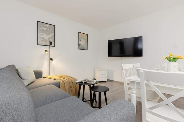 A cozy living area with a modern sofa, a TV, and a small coffee table, decorated in a minimalist style.