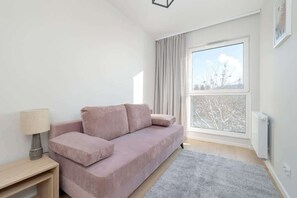 A room with a pink sofa, a large window, and a minimalist design.