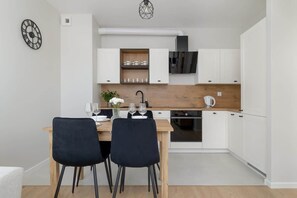 A modern kitchen with white cabinets, a wooden countertop, and a dining table with chairs.